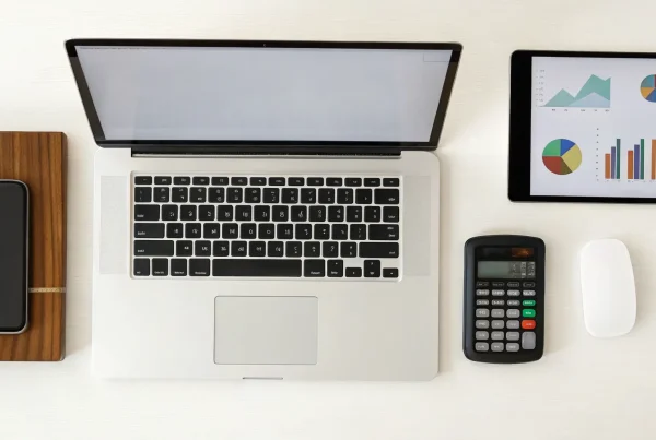 A desk with a laptop and charts for finding the best merchant account for a small business.